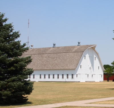 [White barn with sloping grey composite roof and plenty of windows along the side walls.]